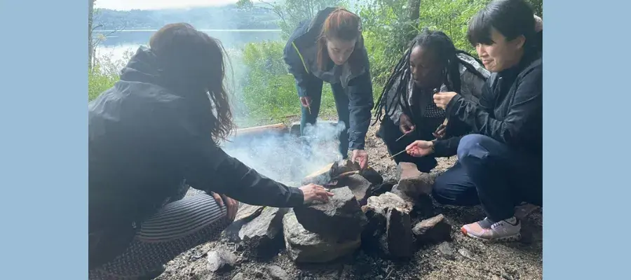 A group of PhD students sitting around a campfire at Firbush – August 2024